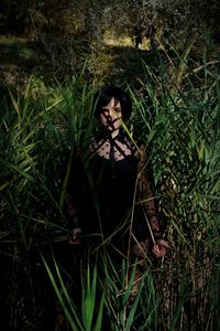 Portrait of woman standing on field in forest