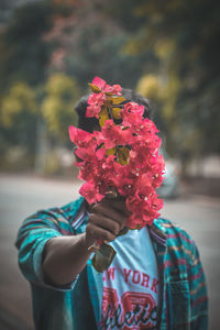 Close-up of person holding red flowering plant