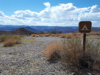 Road sign on field against sky