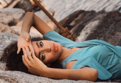 Portrait of young woman lying on rock