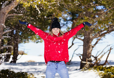 Rear view of woman with arms outstretched standing on snow covered field