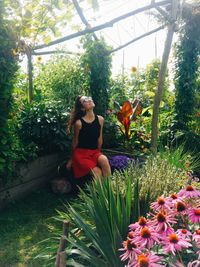 Young woman sitting on plants against trees