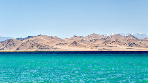 Scenic view of sea and mountains against clear blue sky