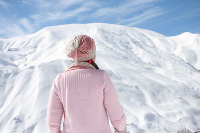 Rear view of woman standing against snow capped mountain