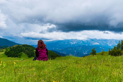 A young female hiker on a break during a hike on a cloudy summer day in the french alps
