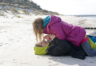 Side view of mother and daughter lying on beach