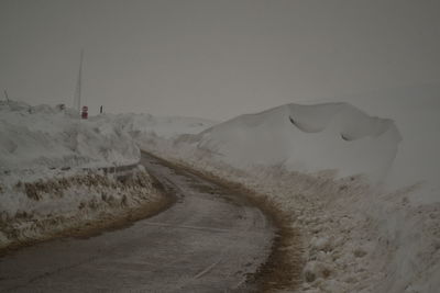 Road leading towards snowcapped mountains against sky