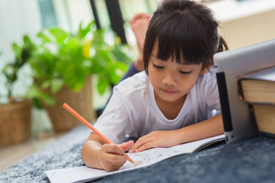 Girl painting while learning over digital tablet at home