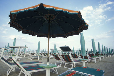 Chairs and parasols on beach against sky