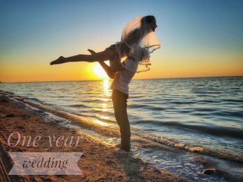 Woman standing at beach against clear sky during sunset