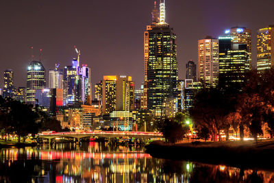 Illuminated buildings in city against sky at night