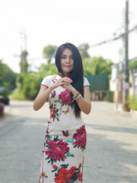 Portrait of young woman standing on road