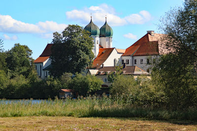 Houses by trees and buildings against sky