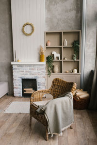 Wicker armchair with a plaid near the fireplace in a country house in the scandinavian-style 