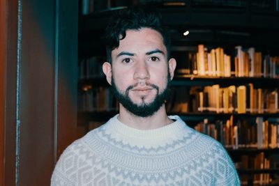 Portrait of young man against bookshelf