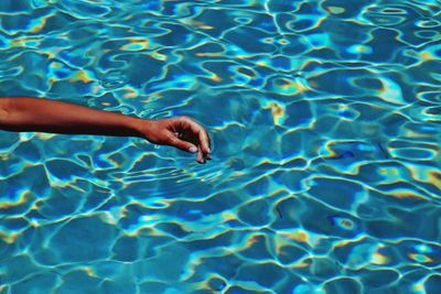 Cropped image of hand on swimming pool