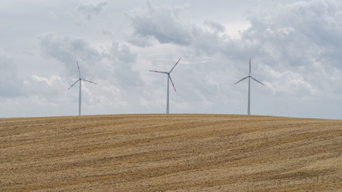 Wind turbines on field against sky