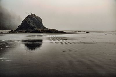 Rock formation on beach against sky