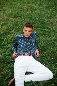 Portrait of young man sitting on field