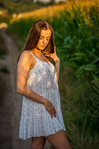 Young beautiful woman in white dress in corn field.