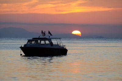 Silhouette boat in sea against orange sky