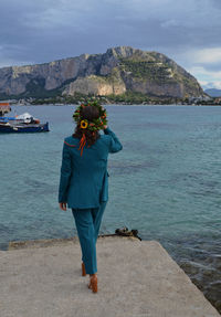 Rear view of woman standing by sea against sky