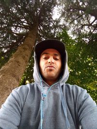 Portrait of young man standing against trees