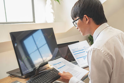 Midsection of man using mobile phone while sitting on table