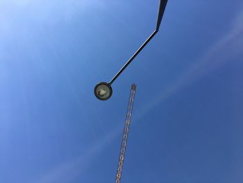 Low angle view of street light by crane against blue sky