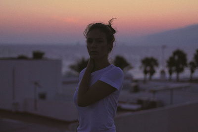 Portrait of young woman standing against sky during sunset