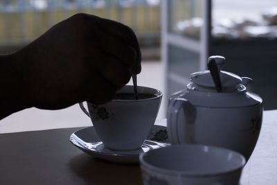 Close-up of hand making coffee in cup