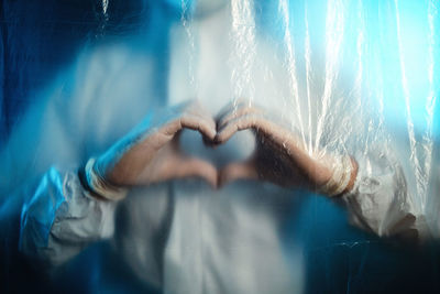 Doctor makes a heart with his hands inside covid ward. coronavirus hospital.