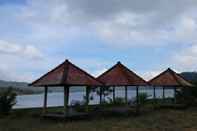 Stilt house on field against sky