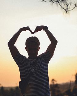 Rear view of man standing against sky during sunset