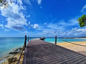 Wooden pier on sea against sky