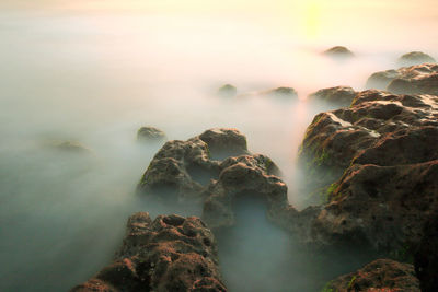 Scenic view of rocks in sea against sky during sunset