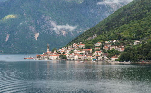 Scenic view of townscape by sea against mountains