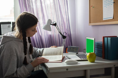 Green screen. a student with braids and glasses at home is reading a book.