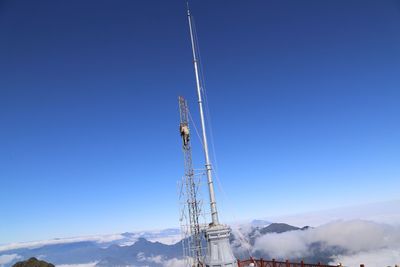 Low angle view of communications tower against blue sky