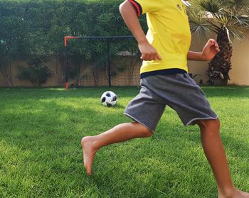Low section of boy playing soccer on grass field at park