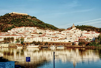 Scenic view of river by buildings against sky