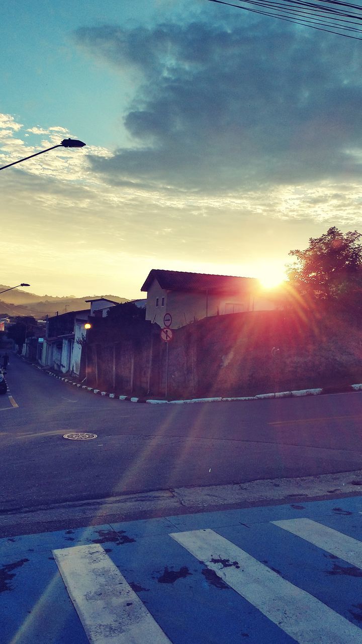 ROAD BY BUILDINGS AGAINST SKY AT SUNSET