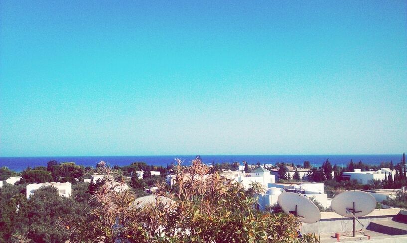 sea, horizon over water, clear sky, copy space, blue, water, beach, building exterior, built structure, architecture, scenics, tranquil scene, nature, shore, beauty in nature, tranquility, high angle view, coastline, day, tree