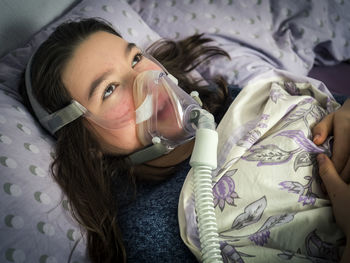 Close-up of girl wearing gas mask while lying down on bed