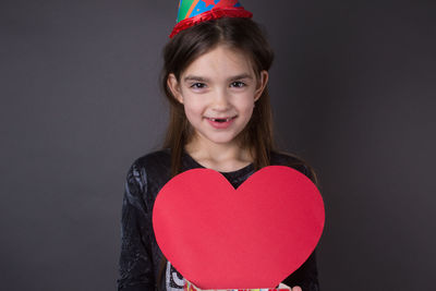 Portrait of girl with heart shape against black background