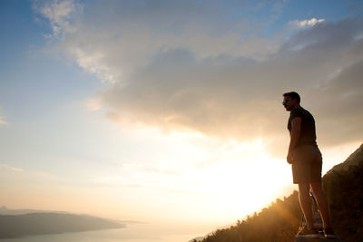 Low angle view of man standing against sky during sunset