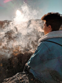 Hiker smoking cigarette while sitting on mountain