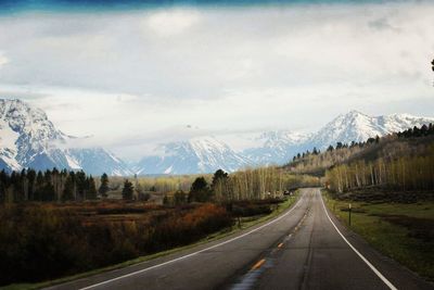 Road leading towards mountains against sky