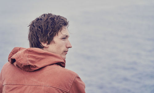 Close-up of young man looking at sea against sky
