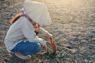 Woman planting while crouching on field